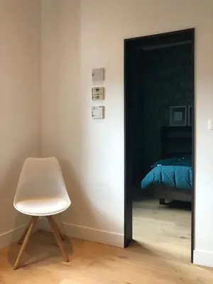 a mirror in a room with a chair and a bed at Gîte Jaja in Limbourg