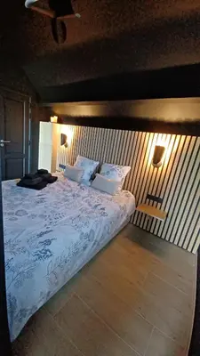 a bedroom with a large bed with two lamps on it at Le Makalle in Dalhem