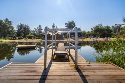 a wooden dock on a body of water at Glamping Limburg - nabij Nationaal Park Hoge Kempen in Kinrooi