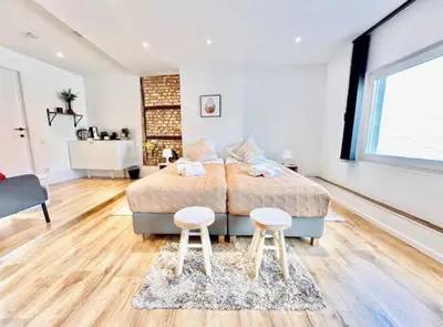 a bedroom with a bed and two stools in it at Logies by Suzan in Hasselt