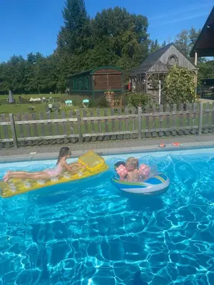two children riding on inflatables in a swimming pool at Margaux B&B Babbita in Stokrooie