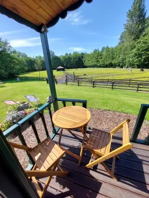 a table and chairs on a deck with a field at Pia B&B Babbita in Hasselt