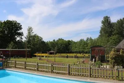 a fence around a swimming pool with a park in the background at Pia B&B Babbita in Hasselt