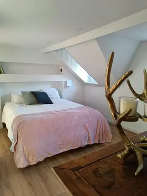 a bedroom with a bed in a room with a slope at Ô Colombages in Les Biolles
