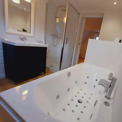 a bathroom with a large white tub and a shower at Ô Colombages in Les Biolles