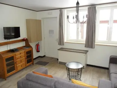 a living room with a couch and a tv at Schophemmerhoeve in Voeren