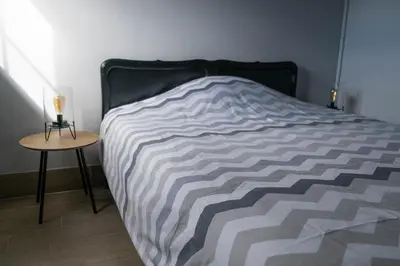 a bed with a black and white comforter and a table at Vakantiewoningen Pomona in Heers