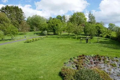 a park with green grass and trees and a road at B&B La ferme de Berwausault in Herve