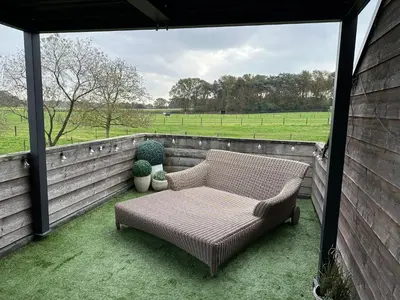 a couch sitting on a porch with a view of a field at Welness gastenverblijf Carpe Diem in Oudsbergen