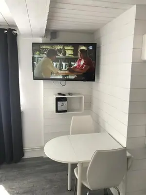 a room with a table and a tv on a wall at Studio Au jardin fleuri in Verviers