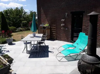 a patio with blue chairs and a table and umbrella at Studio Au jardin fleuri in Verviers