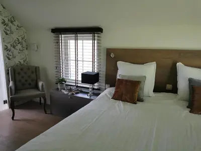 a bedroom with a large bed and a chair at Bed & Bokes aan de Maaskant in Lanaken
