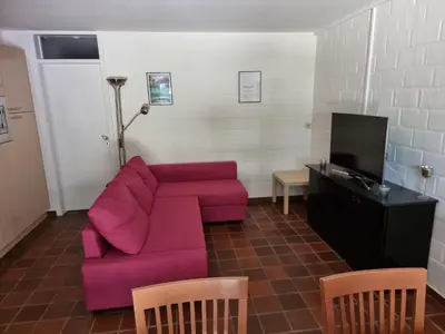 a living room with a pink couch and a tv at Gezellig appartement in groene omgeving in Drijhoeven