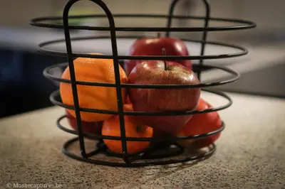 a wire fruit basket with apples and oranges on a counter at De Millenniumhoeve (Willy) in Riemst