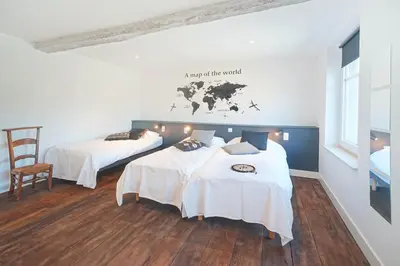a room with two beds with white sheets and a map on the wall at Gîtes Chez Oncle Nicolas in Soumagne
