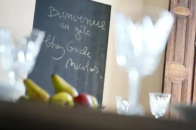 a sign on a table with fruit and glasses at Gîtes Chez Oncle Nicolas in Soumagne