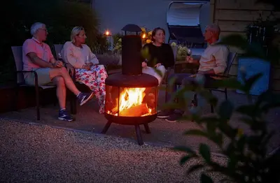 a group of people sitting around a fire in a yard at lit-loo in Hasselt