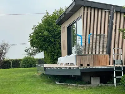 a tiny house with a porch and a deck at Tiny house moderne in Thimister