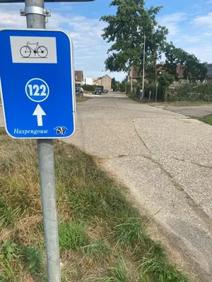 a blue bike sign on the side of a road at Route 123 Birchwood Pension in Kortessem
