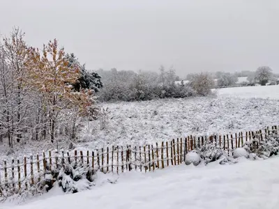 a fence in a field covered in snow at Au cœur de l'Ardenne Bleue - Studio avec piscine in Baelen