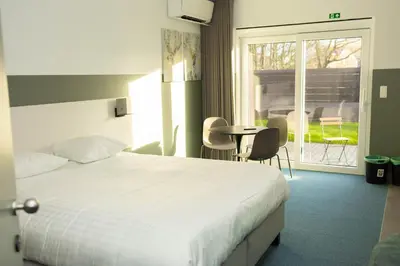 a bedroom with a bed and a table and a window at City Housing Genk in Genk