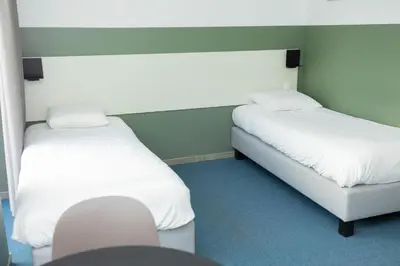 two beds with white sheets in a room at City Housing Genk in Genk