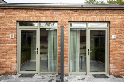 a brick building with three glass doors on it at City Housing Genk in Genk