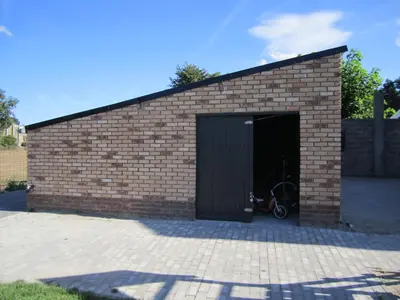a brick building with a garage with a bike in it at De Hoog Velden 13 in Pelt