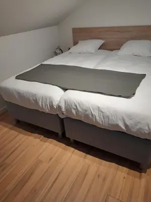 a large bed in a bedroom with a wooden floor at De Hoog Velden 13 in Pelt