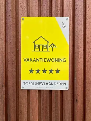 a yellow warning sign on a wooden fence at Shelter in Zutendaal
