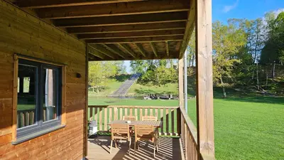 a patio with a table and chairs on a porch at Recreatiedomein Warredal - The Lodge in Neeroeteren