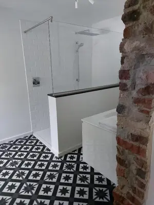 a bathroom with a white shower and a black and white tile floor at Entre Deux Eaux in Lanaken