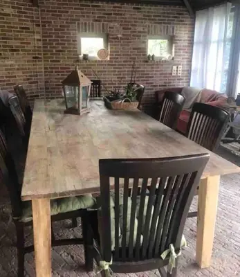 a wooden dining table with chairs and a brick wall at Vakantiehuis de wereldburger Worldcitizen in Oudsbergen