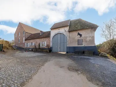 a large brick building with a large door at Riding School Farm Stay in Sint-Truiden
