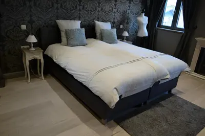 a bedroom with a large bed with white sheets and pillows at Hoeve Lavigne in Wellen