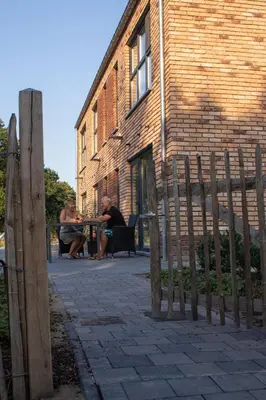 two people sitting at a table in front of a brick building at De Hoog Velden 14 in Pelt