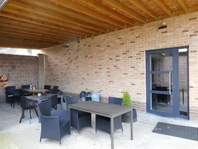 a patio with tables and chairs and a brick wall at De Hoog Velden 14 in Pelt