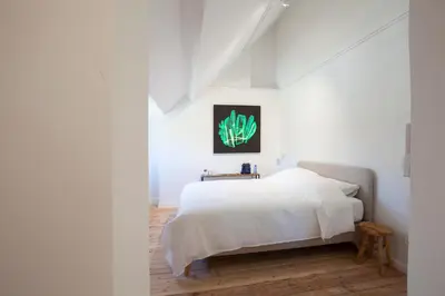 a white bedroom with a bed and a table at Le Charbonnage in Genk