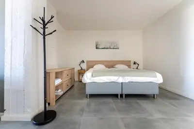 a white bedroom with a bed and a floor at De Hoog Velden 12 in Pelt