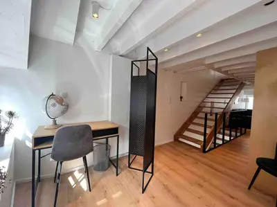a living room with a desk and a staircase at Grand Triplex d'architecte en hypercentre in Liège