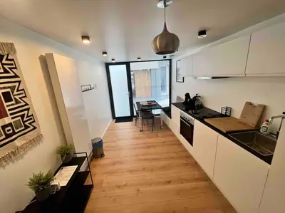 a kitchen with white cabinets and a wooden floor at Triplex d'architecte en hypercentre in Liège