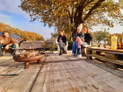 a group of people sitting on a wooden patio at Lodge op de Berg in Bree
