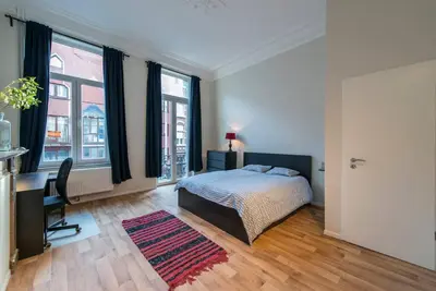 a bedroom with a bed and a desk and windows at Joli appartement 2 chambres à Liège in Liège