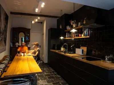 a woman sitting at a wooden counter in a kitchen at Bonjour Pierreuse in Liège