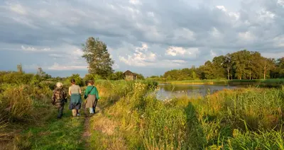 three people walking down a path next to a river at Vakantiewoning De Luysmolen in Bocholt