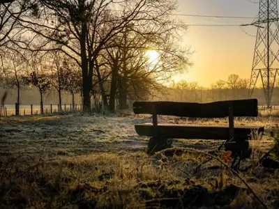 a bench in a field with the sunset in the background at Maasmechelen Duplex Retreat in Maasmechelen