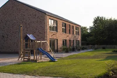 a playground with a slide in front of a brick building at De Hoog Velden 15 in Overpelt