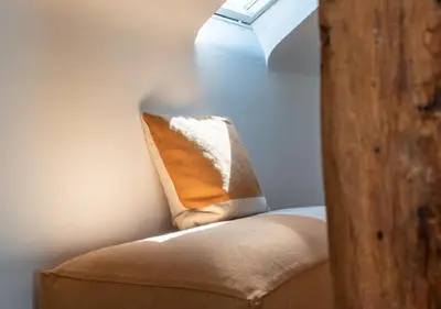 a chair with a pillow sitting under a window at Ca'Triz in Borgloon