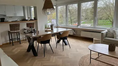 a kitchen with a table and chairs in a living room at Cosy Louvrex -Liège Francorchamps in Liège