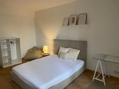 a bedroom with a bed with a lamp and a desk at Cosy Louvrex -Liège Francorchamps in Liège